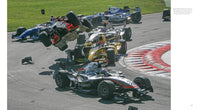 A dramatic moment from Inside Formula 1 by Schiffer Publishing, Ltd.: multiple open-wheel cars crash near red and white curbs, one airborne with debris flying—an intense scene captured in Formula 1 racing photography.